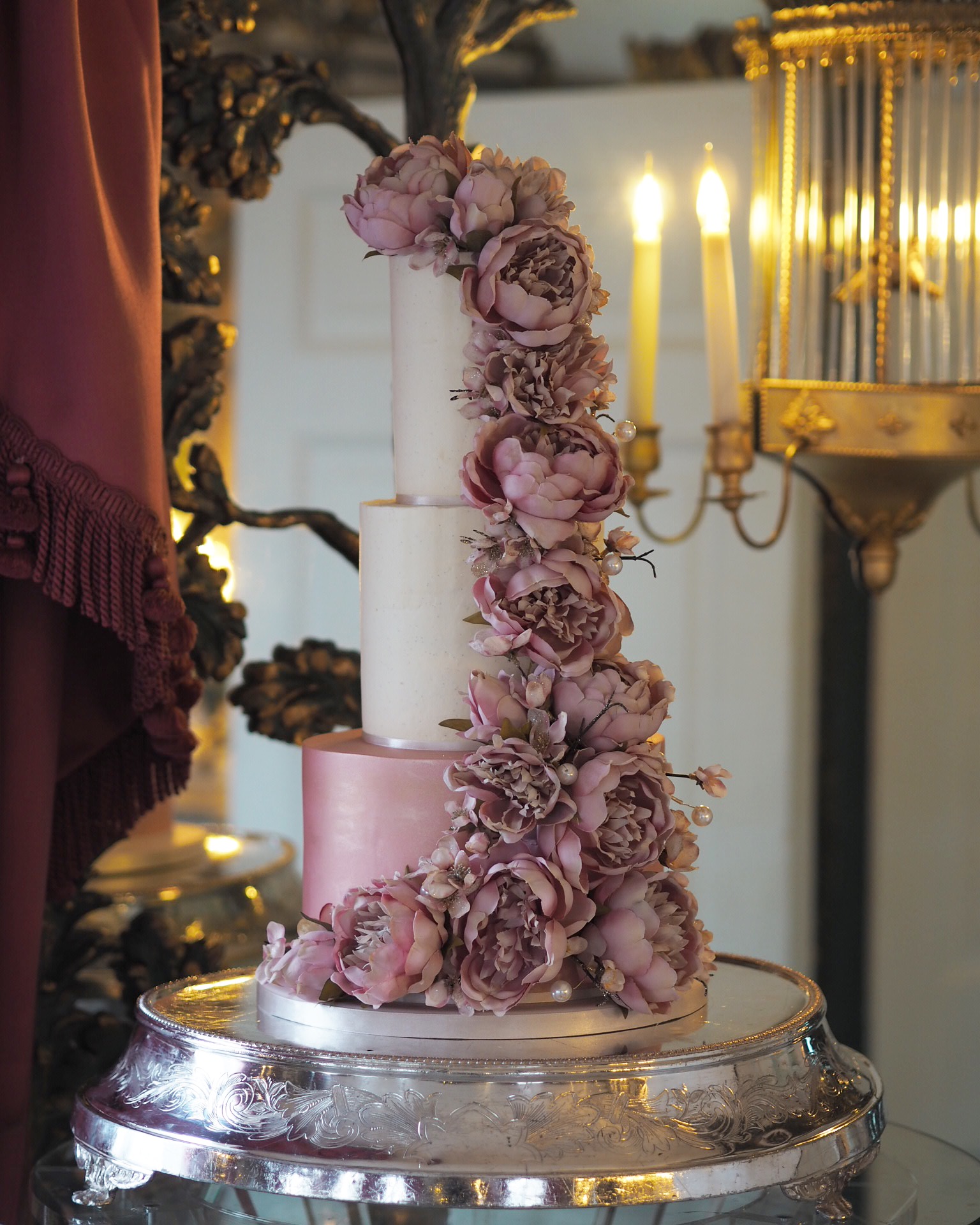 a 3 tier wedding cake in rose gold and ivory with a cascade of silk peonies and blossom at The Dorchester London