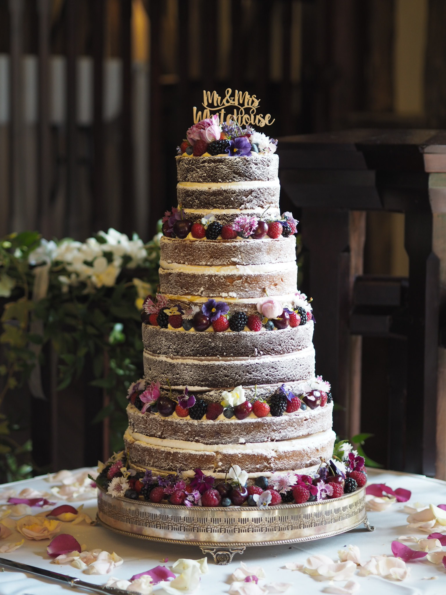 a 4 tier naked wedding cake decorated with fresh fruits and edible flowers at Essendon Country Club wedding venue