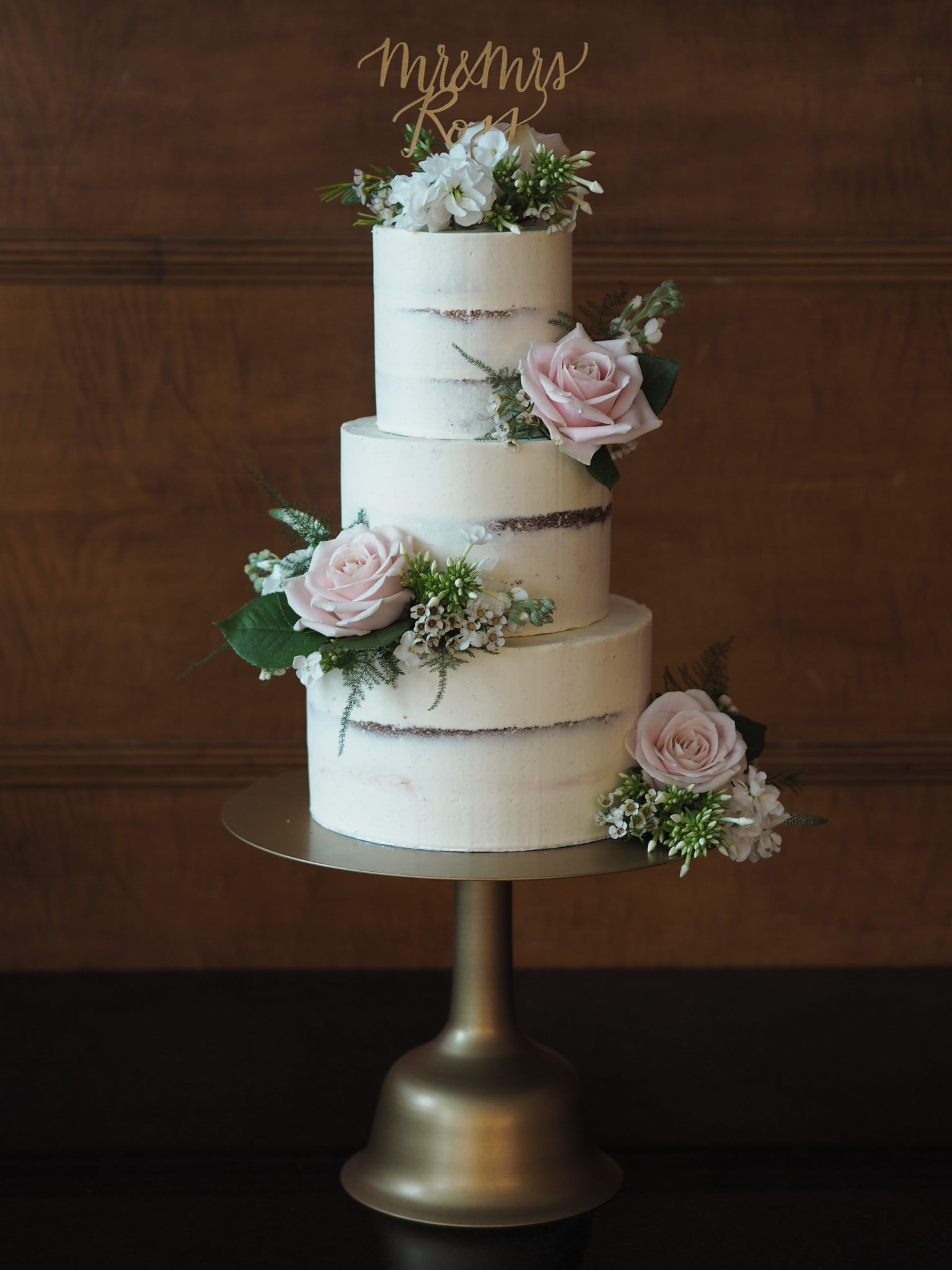a 3 tier semi-naked cake decorated with pale pink and white fresh flowers and calligraphy cake topper at The Town Hall Hotel Bethnal Green
