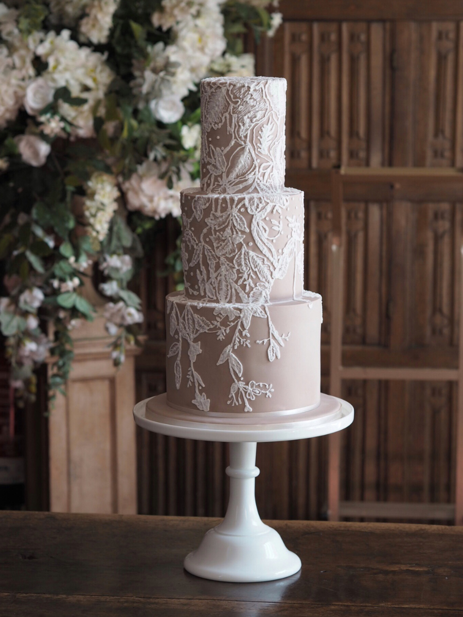 a nude 3 tier wedding cake with bespoke white lace detailing to match the bride's dress at Gosfield Hall wedding venue