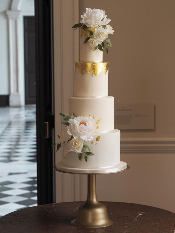 a 4 tier ivory and gold leaf wedding cake with 2 statement sugar flower arrangements with white peonies, white roses and italian ruscus at the Queen's House Greenwich wedding venue